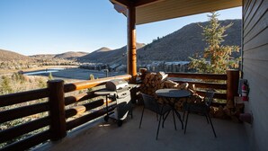 A covered outdoor area with a view of a valley, a grill, chairs, and a table. - Trail's End Lodge at Deer Valley Resort - One Bedroom Residence with Spa #305 1 Condo (Park City)