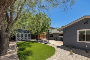 A residential property with a well-maintained lawn, a patio, and a house with a large window.