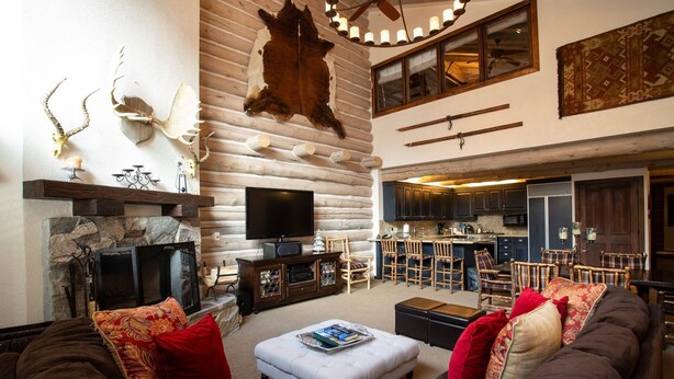 A spacious living room with a fireplace, a television, and a kitchen area visible through an open door. - Pine Inn at Trail's End Lodge - Two Bedroom Condo Residence with Spa #8 by Deer Valley Resort (Park City)