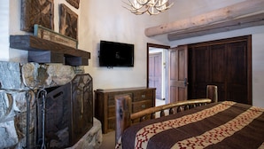 A cozy room with a stone fireplace, a mounted television, and a wooden door. - Pine Inn at Trail's End Lodge - Two Bedroom Condo Residence with Spa #8 by Deer Valley Resort (Park City)