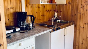 A compact kitchen with wooden walls, a countertop with a coffee maker, a sink, and a dishwasher.