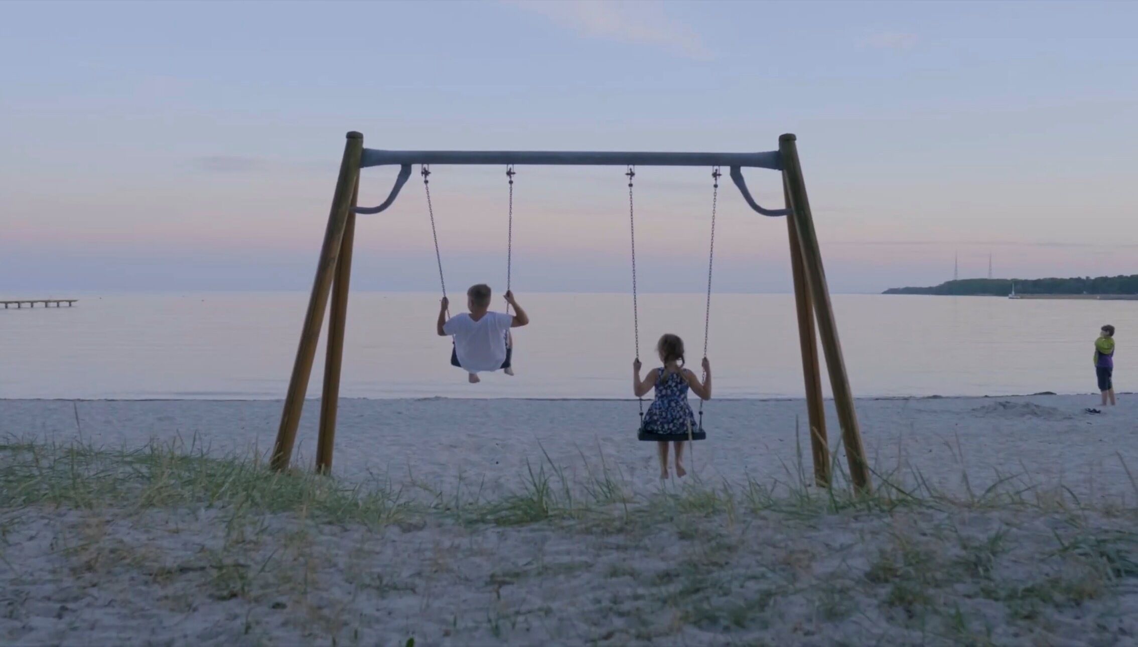 A beach with a swing set and a calm sea in the background.