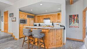 A kitchen with wooden cabinets, a large island with bar stools, a microwave, and a stainless steel range hood. - Trail's End Lodge at Deer Valley Resort - Two Bedroom Residence with Spa #404 2 Condo (Park City)