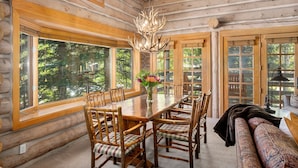 L’intérieur d’une cabane en rondins, avec une table à manger, des chaises et un lustre.