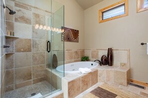 Un baño moderno con ducha envuelta en vidrio, una bañera independiente y un adorno en la pared.