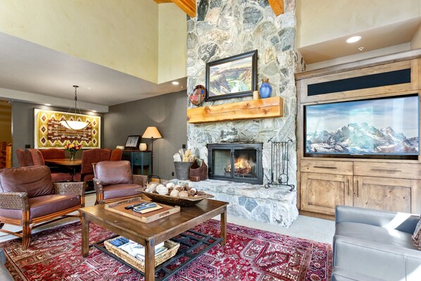 Una sala de estar acogedora con chimenea de piedra, asientos cómodos, un televisor grande y un elemento decorativo en la pared.