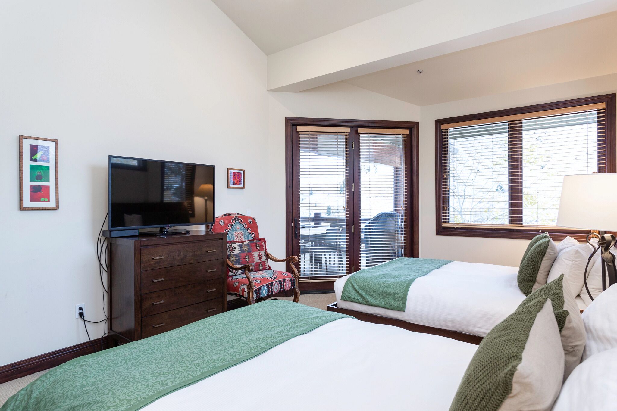 A hotel room with two beds, a TV, a dresser, and a chair.