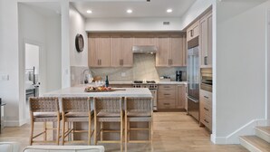 A modern kitchen with wooden cabinets, a central island with bar stools, and built-in appliances. - Trail's End Lodge at Deer Valley Resort - Three Bedroom Residence with Spa #501 3 Condo (Park City)