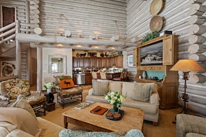 A log cabin interior with a living room, kitchen, and dining area.