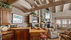 Ein Blockhaus-Interieur mit Kamin aus Stein, Holzmöbeln und einem Essbereich.