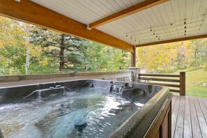 A hot tub area with a wooden deck, surrounded by trees and a view of the forest. - Trail's End Lodge - 4 Bedroom Condo Residence w/ Spa #13 by Deer Valley Resort (Park City)
