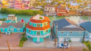 A multi-story house with a unique octagonal roof, situated on a narrow street with a river in the background. - Blizzard's Lighthouse 4 Bedroom Home (Port Isabel)