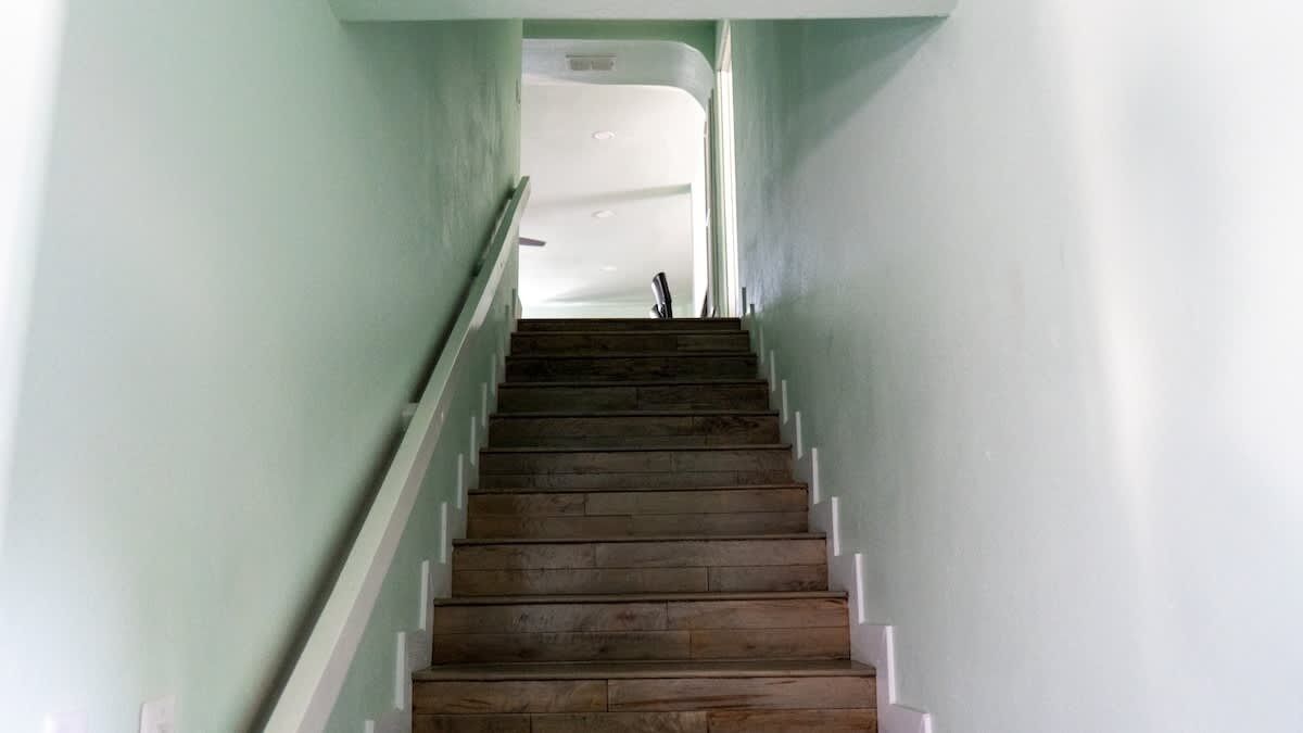 A wooden staircase with white handrails, leading to a door at the top.