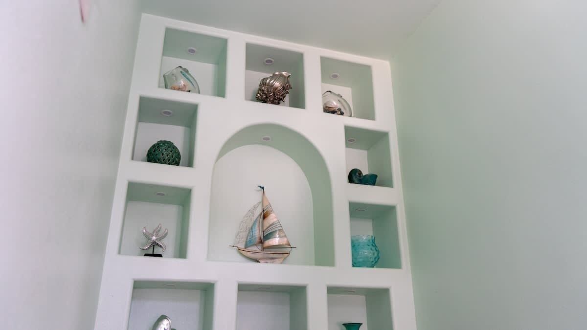 Una pared con múltiples estantes que exhiben varios objetos decorativos.