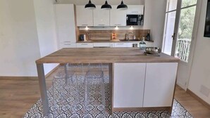 Een moderne keuken met een centraal eiland, witte kasten en een betegelde achterwand.