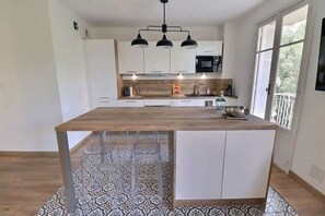 Eine moderne Küche mit einer zentralen Kochinsel, weißen Schränken und einer gemusterten Spritzschutzwand.