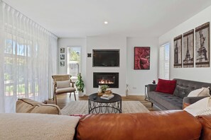 A modern living room with a fireplace, a sofa, a coffee table, and a TV. - Inn McDowell - Modern 3-Bed, Minutes to Te Puia (Rotorua)