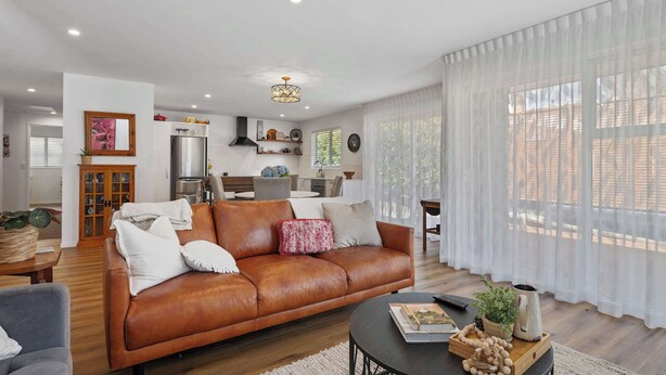 A modern living room with a leather sofa, a dining area, and a kitchen in the background. - Inn McDowell - Modern 3-Bed, Minutes to Te Puia (Rotorua)