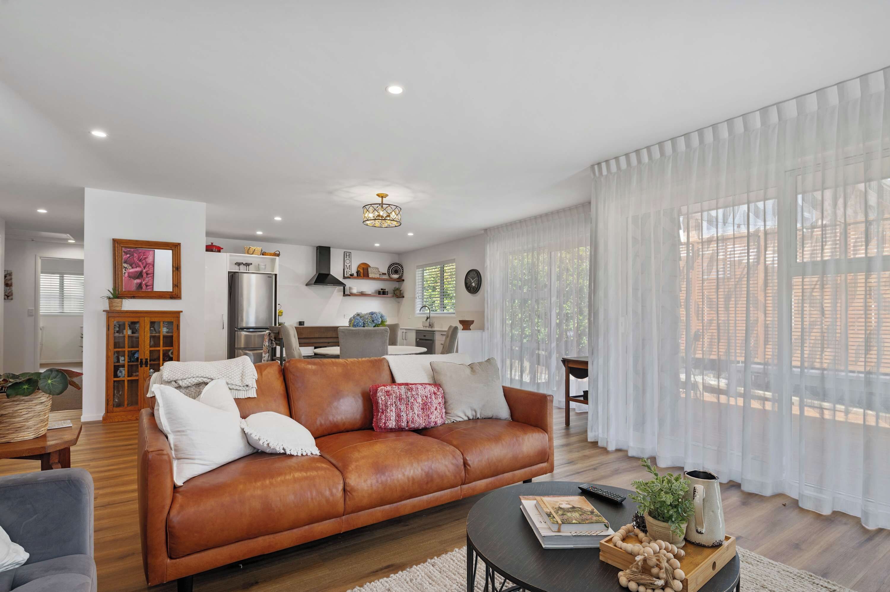 Un soggiorno moderno con un divano in pelle, un'area pranzo e una cucina sullo sfondo.