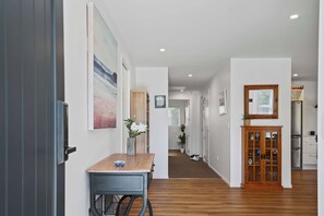 A hallway with a wooden table, a cabinet, and a door leading to a kitchen. - Inn McDowell - Modern 3-Bed, Minutes to Te Puia (Rotorua)