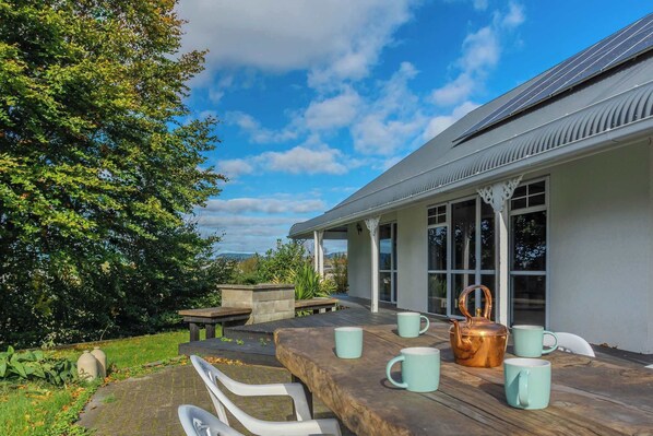 A patio with a table set for tea, a copper teapot, and matching cups.