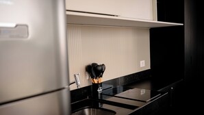A kitchen with a black countertop, stainless steel appliances, and a knife block. - DAWN 145 (Vila Olímpia São Paulo)