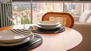 A dining table with plates, glasses, and a chair in a room with a view of buildings. - DAWN 145 (Vila Olímpia São Paulo)