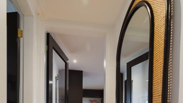 Ein Flur mit einem großen Spiegel, Holzboden und Glastüren zu einem Küchenbereich.