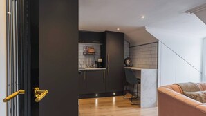 Eine moderne Küche mit dunklen Schränken, Holzboden und einem Essbereich mit Stuhl und Tisch.