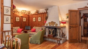 Una sala de estar acogedora con paneles de madera, una chimenea y un comedor con sillas y una mesa.