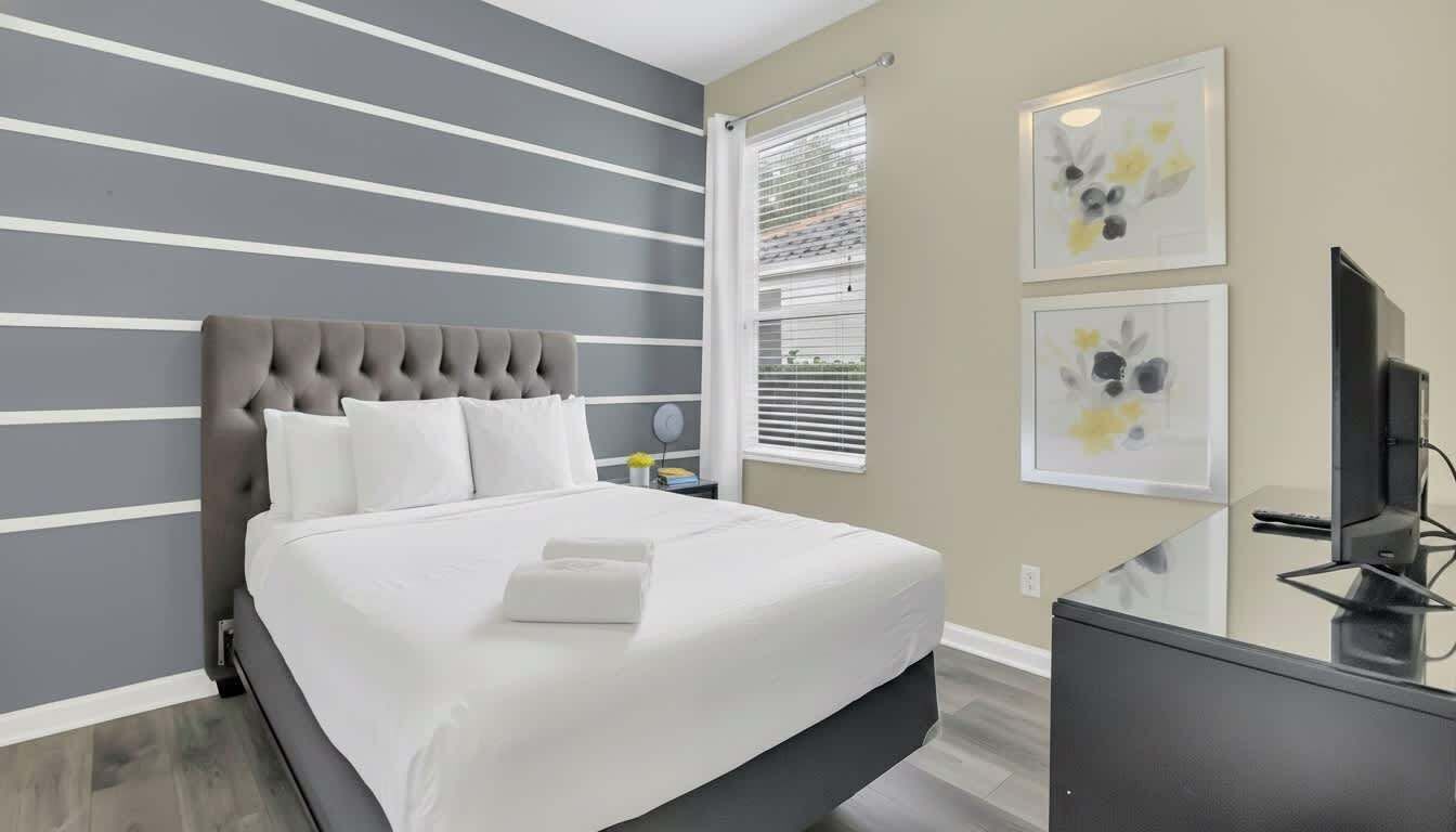 Une chambre moderne avec un grand lit, un téléviseur à écran plat et des œuvres d’art accrochées aux murs.