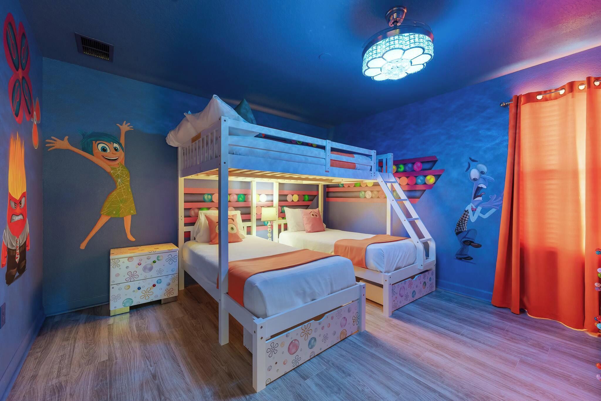 A child-friendly room with bunk beds, a colorful wall mural, and a ceiling light fixture.