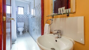 Un baño con lavamanos blanco, inodoro y zona de ducha.