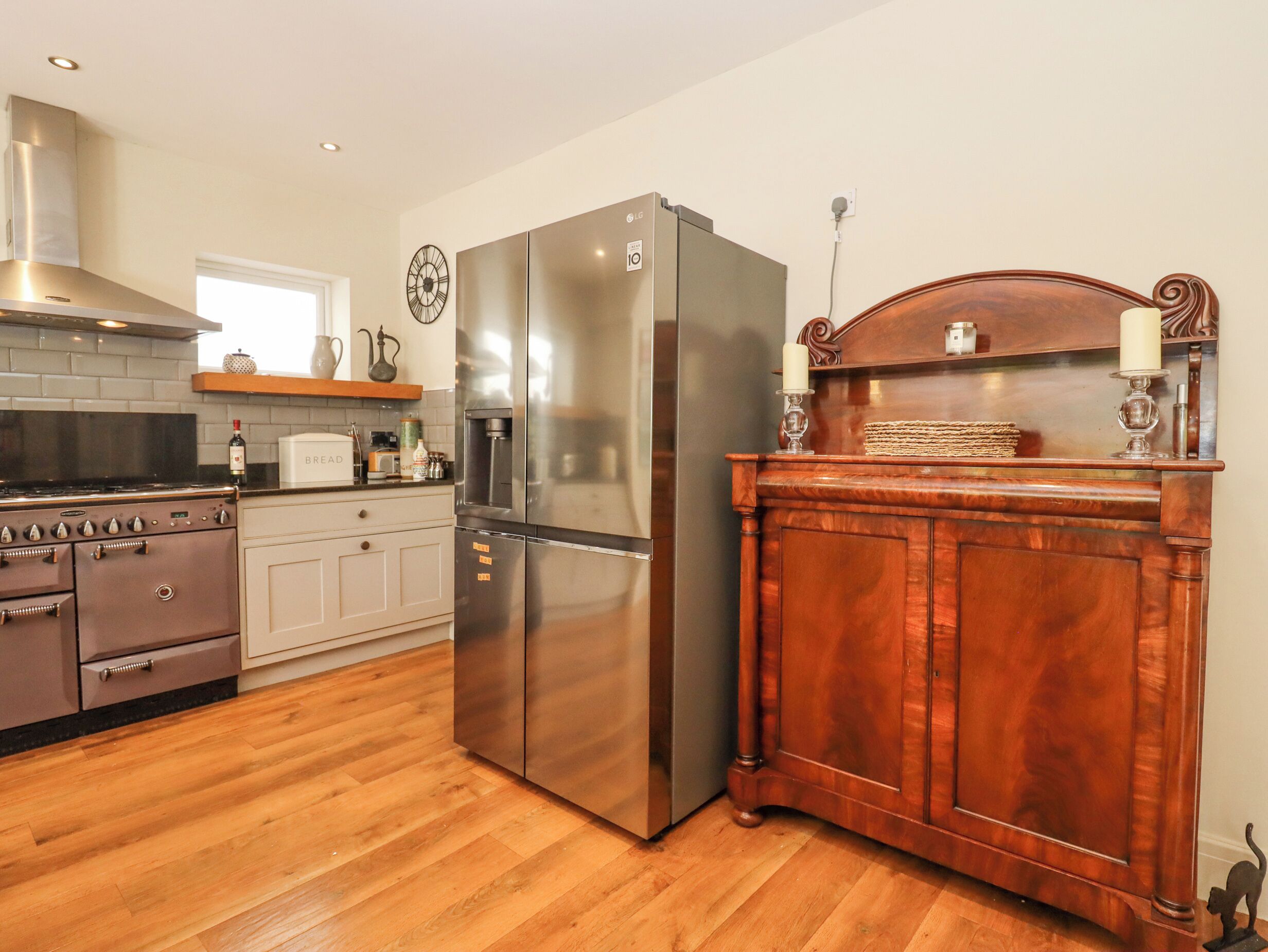 A kitchen with a stainless steel refrigerator, a wooden cabinet, and a vintage stove.