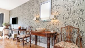 A dining area with a wooden table, chairs, a vase, and a television on the wall. - Hathaway Lane (Stratford-upon-Avon)