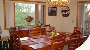 Un comedor con una mesa y sillas de madera, una araña y obras de arte en las paredes.