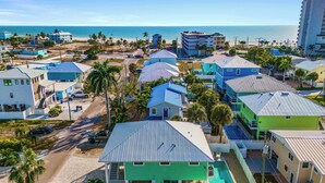 A coastal residential area with houses, a swimming pool, and a beach in the background.