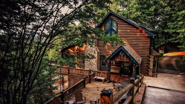 A log cabin with a deck, outdoor seating, and a stone fireplace. - Heinrich's Hideaway Blue Ridge, GA (MORGANTON)
