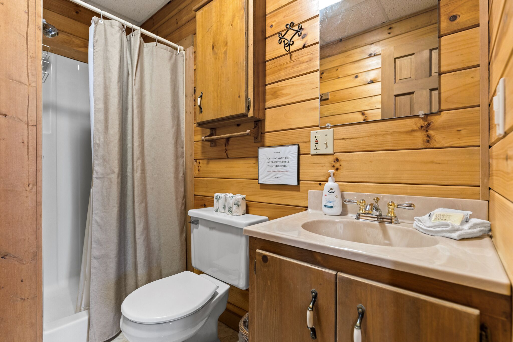 Bagno con rivestimento in legno, dotato di WC, lavandino e tenda per la doccia.