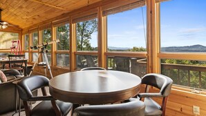 A wooden-paneled room with a round table and chairs, large windows, and a telescope. - Heinrich's Hideaway Blue Ridge, GA (MORGANTON)