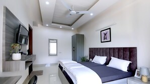 A modern bedroom with a bed, bedside tables, a TV, and a ceiling fan. - Housr Sector 43 Gurgaon Global FoyerMall (Gurugram)