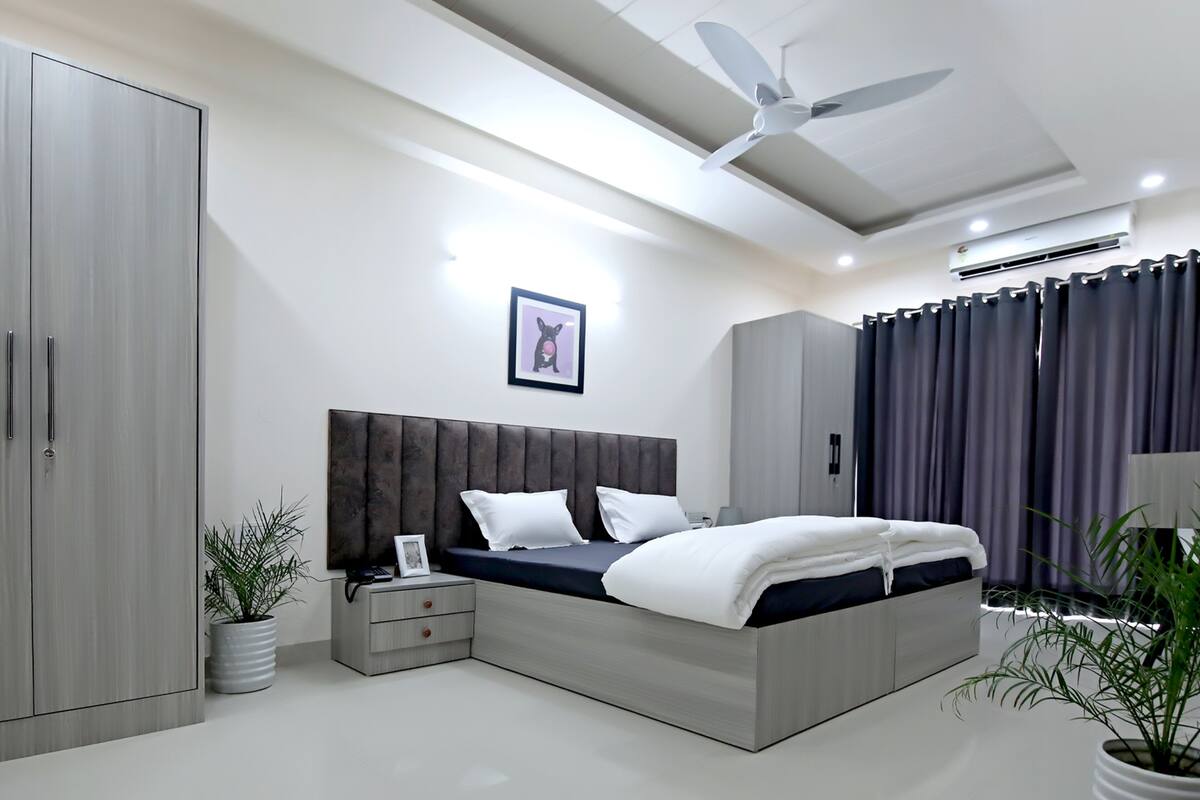 Een moderne slaapkamer met een bed, een kledingkast, nachtkastjes en een plafondventilator.