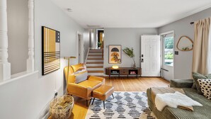 A spacious living area with a staircase leading to another level, a sofa set, a coffee table, and a decorative mirror.