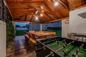 An indoor recreational area with a foosball table, a dining table set for four, and a dartboard.