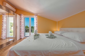 A hotel room with a large bed, white linens, a balcony with glass doors, and a view of greenery. - Villa Sami Zadar Villas (Benkovac)