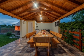 An outdoor dining area with a wooden table and benches, surrounded by a wooden fence and a garden. - Villa Sami Zadar Villas (Benkovac)
