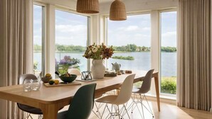 A dining area with a large table, chairs, and a view of a lake.