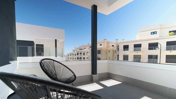 Un balcone con una sedia, un tavolo e vista sugli edifici.
