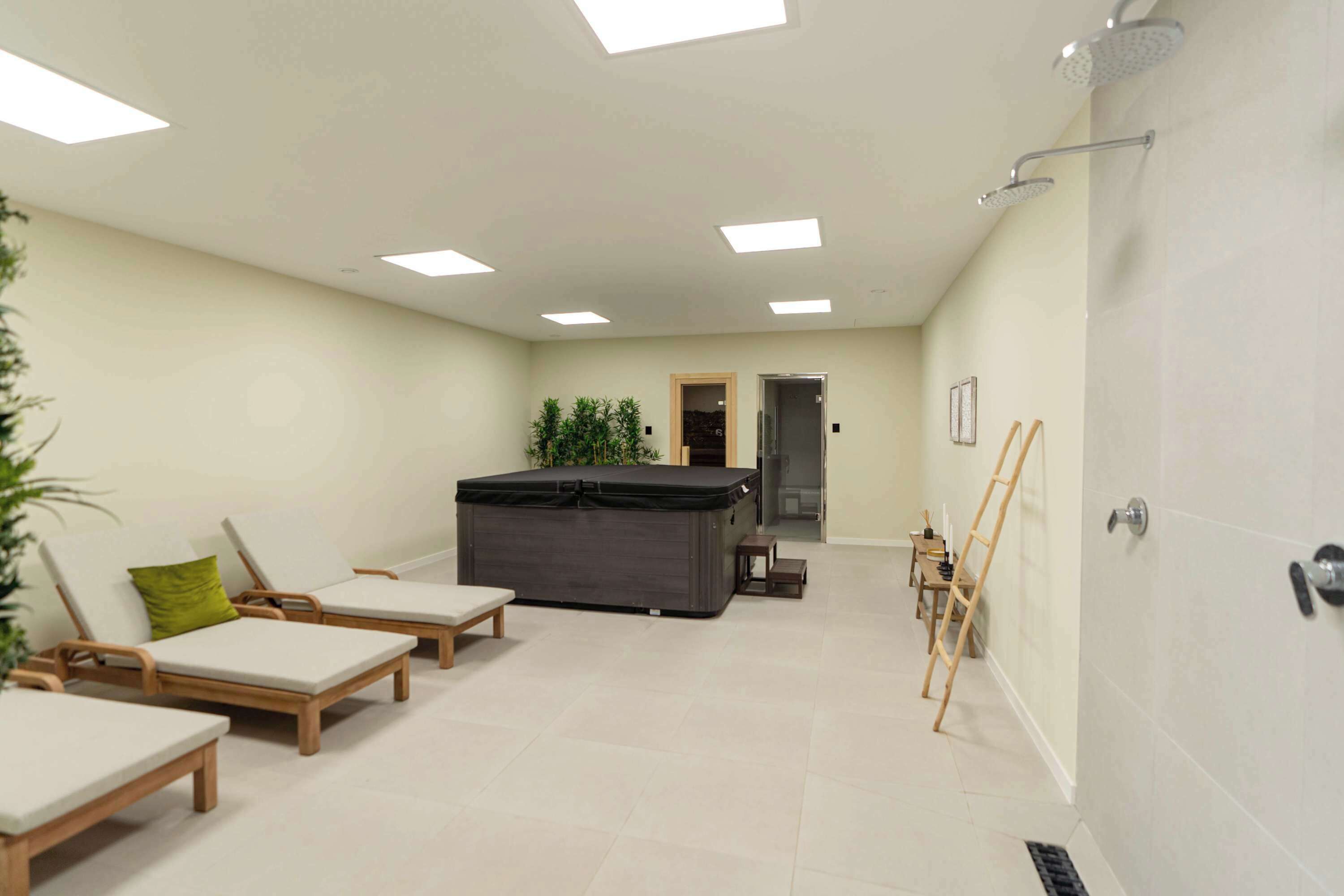 Un espace bien-être comprenant un jacuzzi, des chaises longues et une douche.