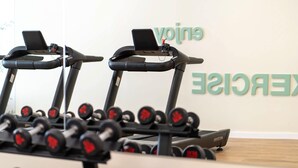 Una palestra con tapis roulant e un espositore di manubri.